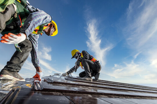 Two male workers wearing safety clothes Installing the roof tile house That is a ceramic tile roof On the construction site