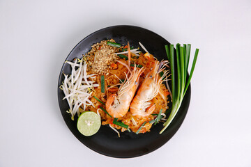 Udon noodle pad thai with shrimp in black plate white background top view asian food Copy space