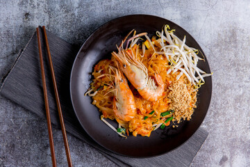 Udon Pad Thai with shrimp in a dark background, top view Asian style food Copy space