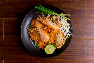 Udon Pad Thai with shrimp in a dark background, top view Asian style food Copy space