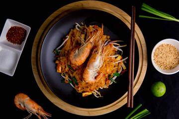 Udon Pad Thai with shrimp in a dark background, top view Asian style food Copy space