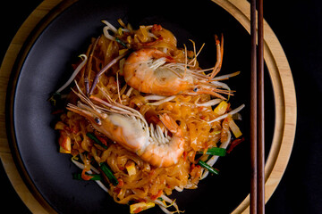Udon Pad Thai with shrimp in a dark background, top view Asian style food Copy space