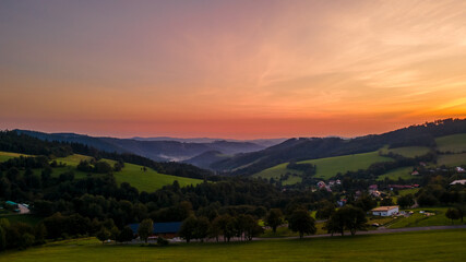 Fototapeta premium Aerial view of a hill on the Bystricka dam and the surrounding hills during sunset between the valley appears fog.