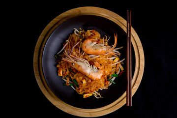 Udon Pad Thai with shrimp in a dark background, top view Asian style food Copy space