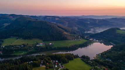 Fototapeta na wymiar Aerial view of a hill on the Bystricka dam and the surrounding hills during sunset between the valley appears fog.