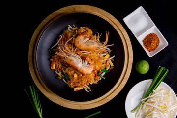 Udon Pad Thai with shrimp in a dark background, top view Asian style food Copy space