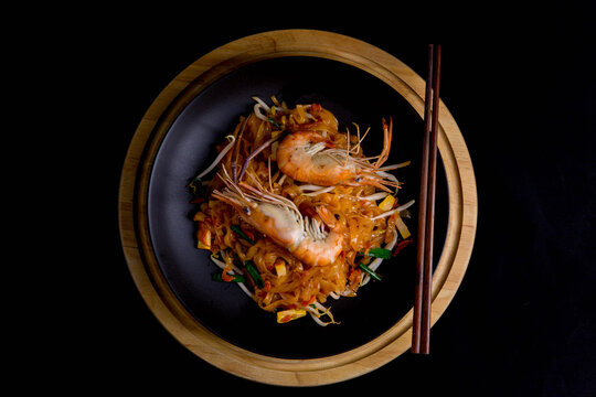 Udon Pad Thai with shrimp in a dark background, top view Asian style food Copy space