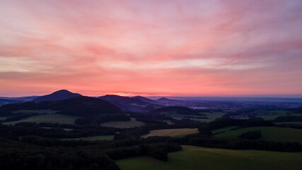 Obraz na płótnie Canvas Aerial view of colorful clouds and mountainous hilly landscape at sunset over the horizon of Beskydy region.