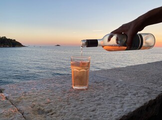 Rovinj Istrien Kroatien Adria Mittelmeer - Flasche Rose Wein wird im Sonnenuntergang auf einem Stein Tisch ausgeschenkt