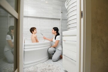 Obraz na płótnie Canvas Mother washing little son in bathroom