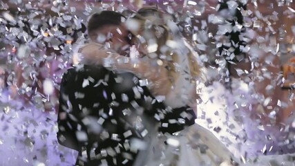 Beautiful blond bride and handsome groom dancing first dance at the wedding party. Confetti in the air. Very tender moment - Powered by Adobe