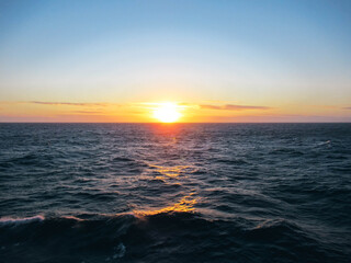 Sunset at sea with sunlight reflecting from waves.