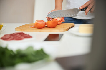 Carefully slicing vegetables on the wooden board