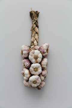 Rustic plaited string of garlic on a light grey clean and neutral table.