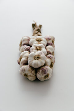 Rustic plaited string of garlic on a light grey clean and neutral table.