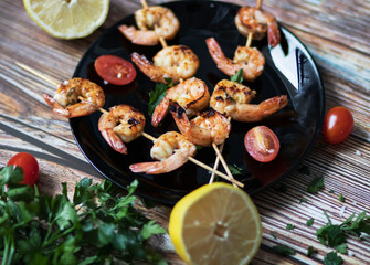 
Shrimp shashlik in a pan, fried in oil and with spices. All this is on the table. Nearby is a plate of shrimp shashals
