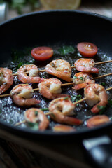 
Shrimp shashlik in a pan, fried in oil and with spices. All this is on the table. Nearby is a plate of shrimp shashals