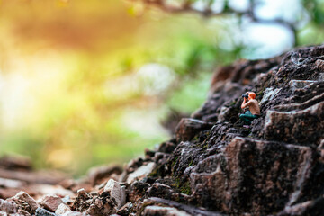 Miniature photographer taking photo of beautiful landscape