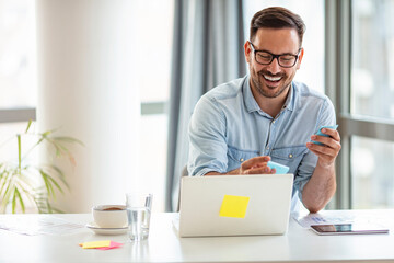 Smiling young man using laptop studying working online at home, happy casual millennial guy typing...