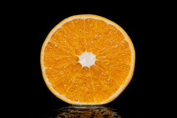 orange on a black background with splashing water and with reflection. Vitamins and health.