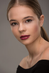 portrait of a beautiful teen girl with exquisite makeup with red lipstick on a gray background