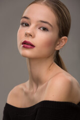 Fototapeta premium portrait of a beautiful teen girl with exquisite makeup with red lipstick on a gray background