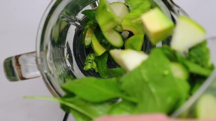 Cooking green smoothie in blender. top view. Healthy detox concept. Green fruits and vegetables fall in blender. slow motion