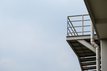 Fototapeta premium Exterior metal staircase of the building with cloud sky in background. Outdoors staircase of the building.