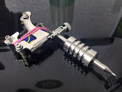 M&aacute;quina para tatuar con tubo sobre mesa de cristal negro