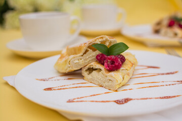 Roll with cottage cheese and raspberries poured with soft caramel on a white ceramic plate.
