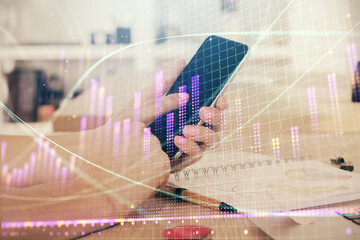 Double exposure of man's hands holding and using a digital device and forex graph drawing. Financial market concept.