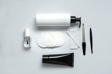 Many small items for individual use lie on a white canvas. These are ear sticks, nail file, nail polish, cotton pads, tube of cream, dispenser.