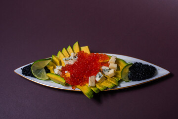 avocado slices with red and black caviar and cheese with mold on a plate