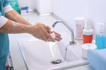 Surgeon washing his hands at hospital cleaning room during Coronavirus outbreak - Focus on right hand