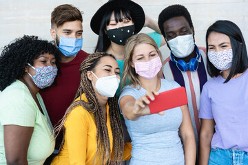 Multiracial friends taking a selfie while wearing mask outdoor - Social distance concept