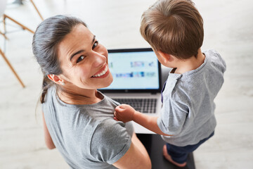 Fröhliche Mutter mit Sohn am Laptop Computer
