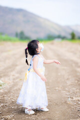 Portrait adorable Asian child girl wearing medical face mask in white dress. Children looked up at something on the sky. Protective corona virus disease and pm2.5. Join the wedding New Normal  style.