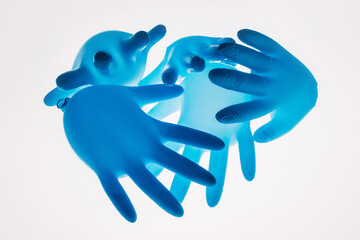 Pandemic art. Social distance. Covid-19 lockdown. Quarantine safety measures. Blown blue protective medical hand gloves floating on air in group isolated on white background.