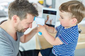 Junge beim Fieber messen beim Vater im Videochat