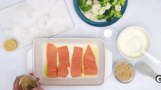 Baked salmon and vegetable casserole recipe. Topping raw fish fillet with marinade