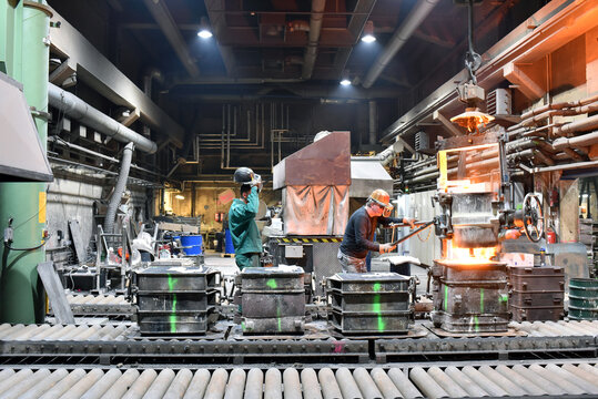 group of workes in a foundry - production in steelworks - industrial building inside