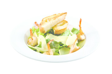 Seafood Caesar salad with shrimp, arugula, and parmesan cheese on a round white plate. Isolated. White background.