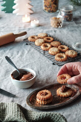 Christmas Linzer cookies filled on cooling rack, metal plate. Sandwich cookies filled with hazelnut...