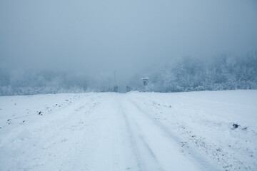 Fototapeta na wymiar Snowy road in the winter day . Hard road in the Foggy Day 
