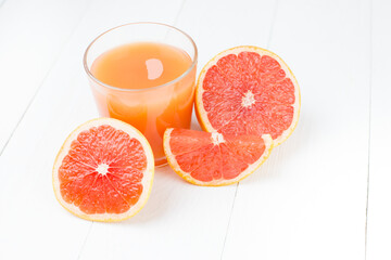 A glass of grapefruit juice and fresh grapefruit on a white wooden table close-up. Citrus vitamin juice in a clear glass with fruit. copy space