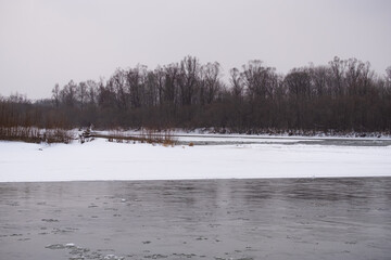 Mountain Russian river in winter. Snow on the shore. Rapid flow of ice water.