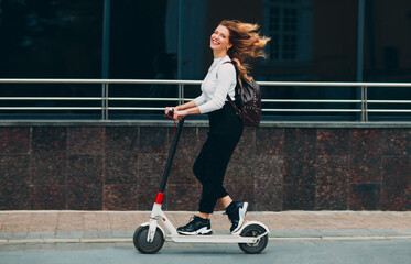 Young woman with smile ride electric scooter at the street