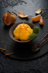 Tangerine ice cream in a cup on a black background