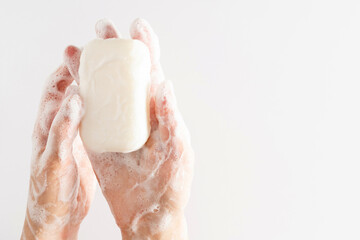Washing of hands with soap. Cleaning hands. Closeup on young woman hands with soap bar on white background.
