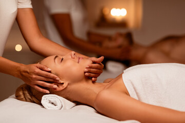 Woman Receiving Face Massage During Couples Therapy Lying In Spa